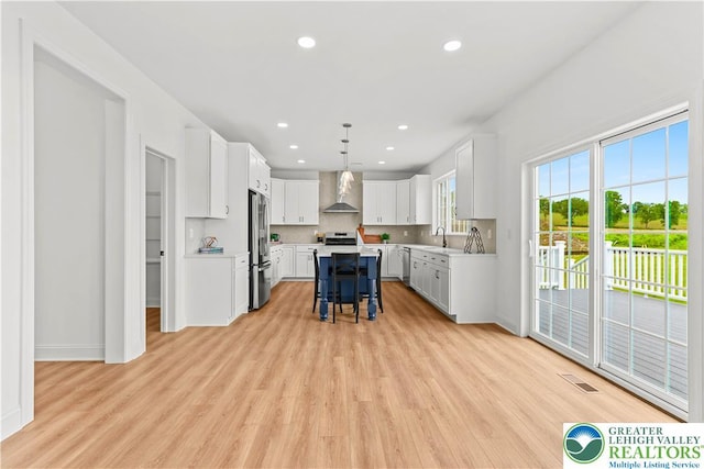 4779 Farrcroft Dr Unit 90, Forks Twp, PA 18040 - kitchen featuring wall chimney range hood, stainless steel appliances, a sink, a kitchen breakfast bar, and light wood-type flooring