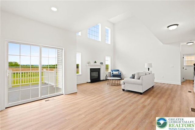 4779 Farrcroft Dr Unit 90, Forks Twp, PA 18040 - living area featuring light wood-type flooring, baseboards, a glass covered fireplace, and a towering ceiling