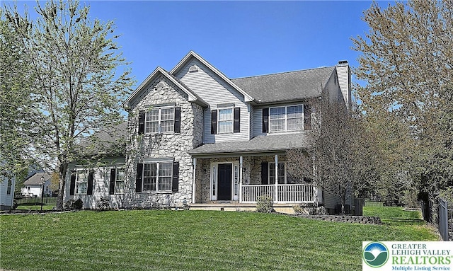 traditional-style house featuring stone siding, covered porch, and a chimney