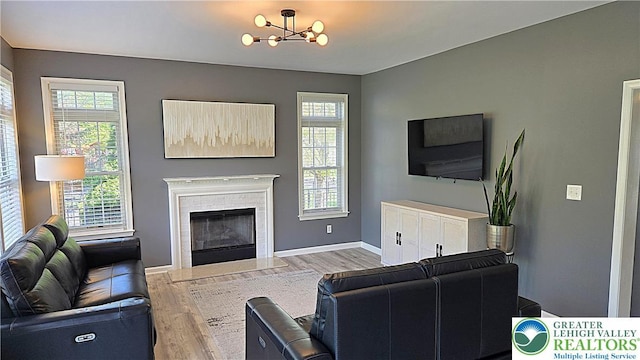 living area featuring wood finished floors, a chandelier, healthy amount of natural light, and a fireplace