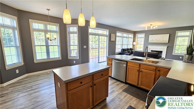 kitchen with stainless steel dishwasher, a sink, open floor plan, light wood-style floors, and a center island
