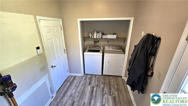 clothes washing area with washing machine and clothes dryer, dark wood finished floors, and baseboards