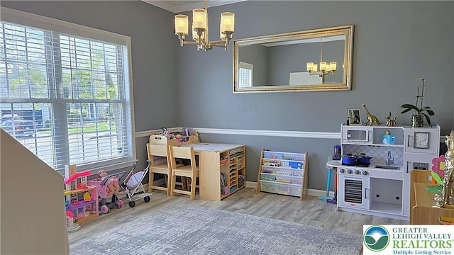 recreation room featuring a chandelier, ornamental molding, and wood finished floors