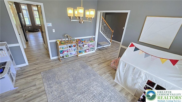 rec room with baseboards, wood finished floors, and a chandelier