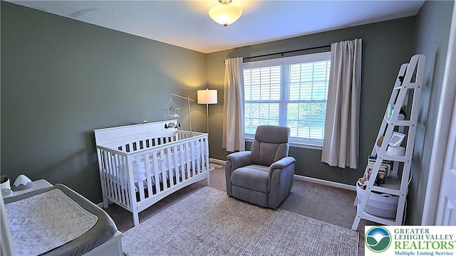 carpeted bedroom featuring baseboards and a nursery area