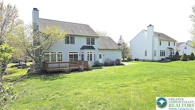 rear view of house featuring a deck, a yard, and a chimney