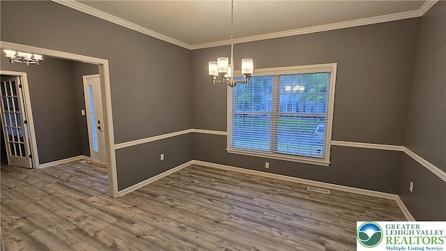 unfurnished room featuring a chandelier, crown molding, wood finished floors, and baseboards