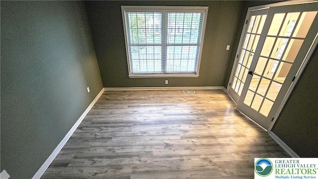 empty room featuring plenty of natural light, baseboards, and wood finished floors