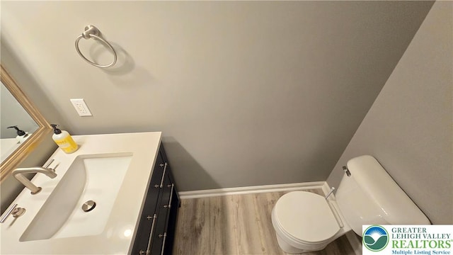 bathroom with wood finished floors, toilet, vanity, and baseboards