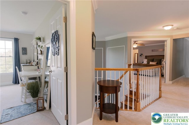 hall featuring carpet floors, an upstairs landing, crown molding, and baseboards