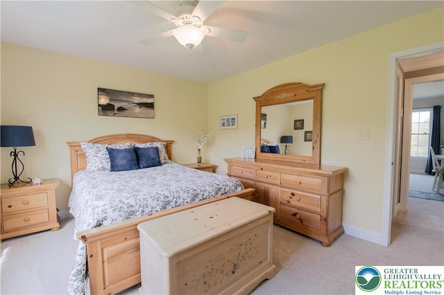 bedroom featuring light colored carpet, baseboards, and a ceiling fan