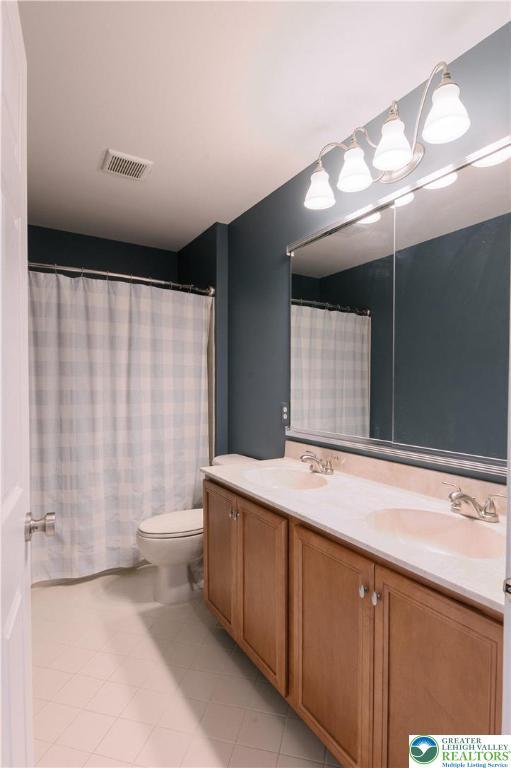 bathroom featuring double vanity, tile patterned flooring, and toilet