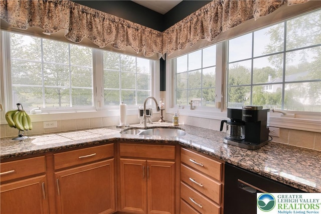 kitchen featuring a sink, black dishwasher, brown cabinets, and stone counters