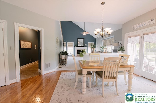 dining space featuring healthy amount of natural light, a chandelier, light wood-type flooring, baseboards, and lofted ceiling