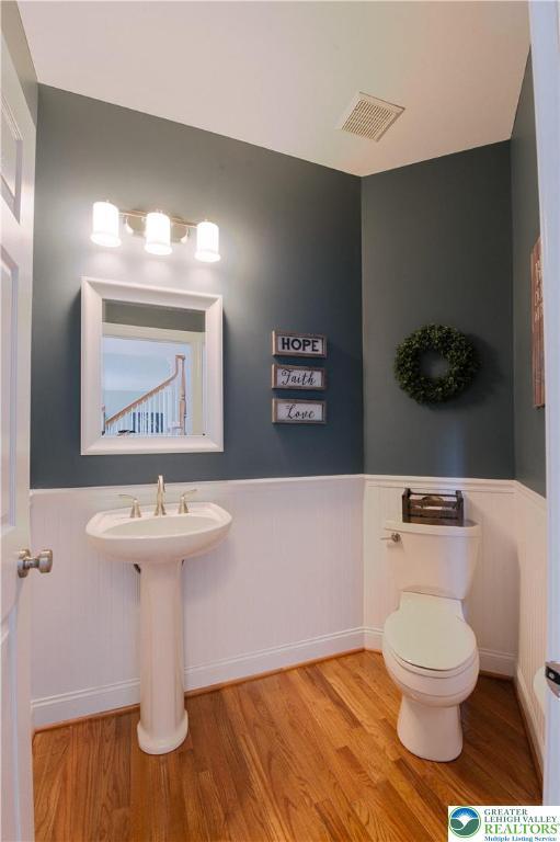 bathroom featuring wainscoting, wood finished floors, and toilet