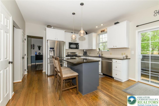 kitchen with appliances with stainless steel finishes, dark wood finished floors, a center island, white cabinetry, and recessed lighting