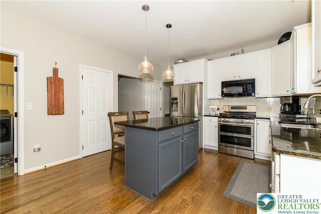 kitchen with black microwave, double oven range, a sink, and white cabinets