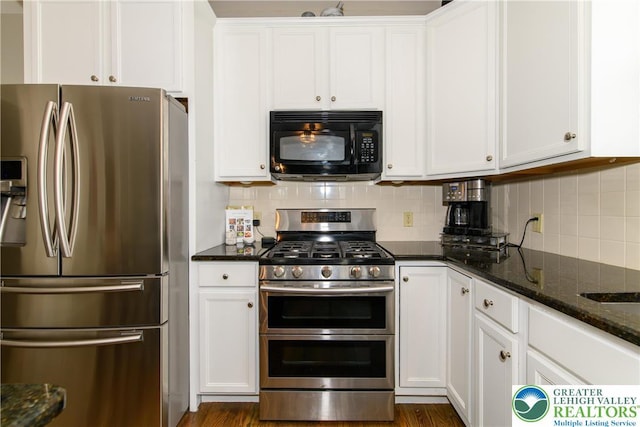 kitchen featuring stainless steel appliances, white cabinets, dark stone countertops, and tasteful backsplash