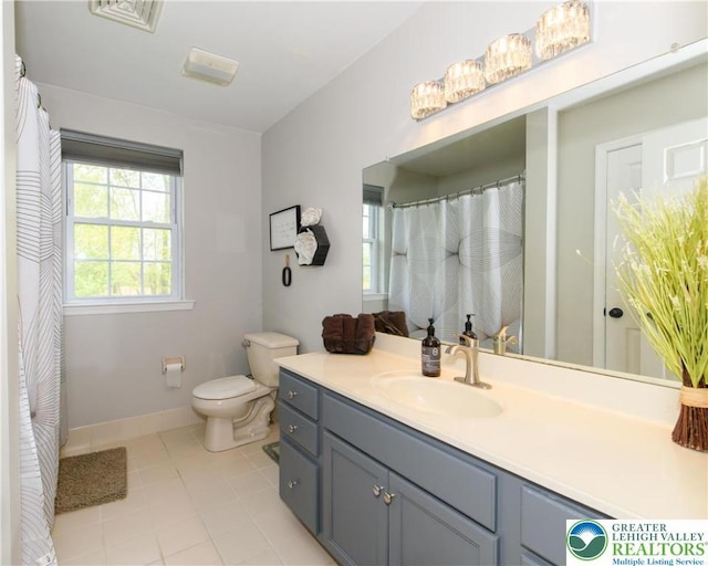 bathroom with toilet, vanity, tile patterned floors, and baseboards