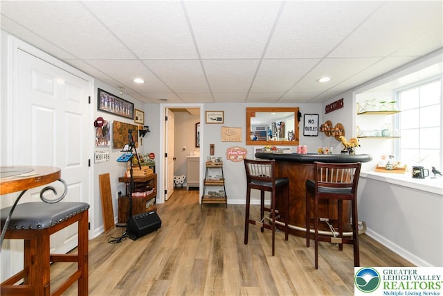 indoor dry bar featuring light wood-type flooring, a drop ceiling, baseboards, and recessed lighting