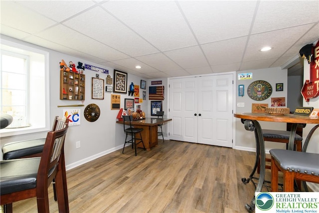 dining space featuring a drop ceiling, baseboards, wood finished floors, and recessed lighting