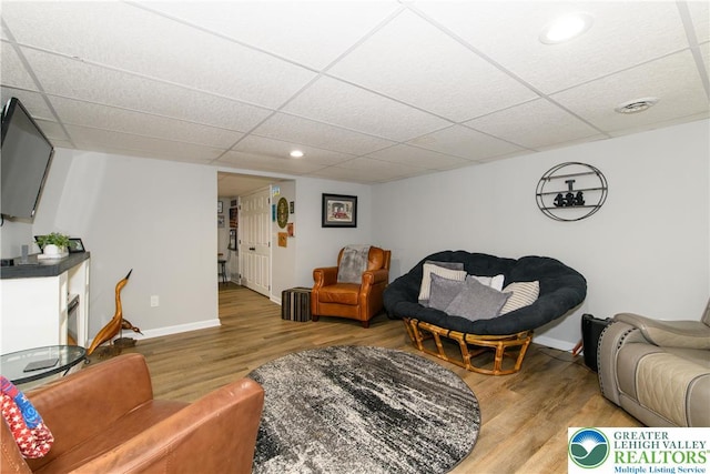 living area featuring light wood finished floors, a paneled ceiling, baseboards, and recessed lighting