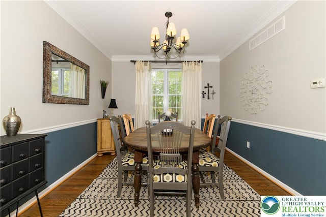 dining space featuring dark wood-style flooring, a chandelier, ornamental molding, and baseboards