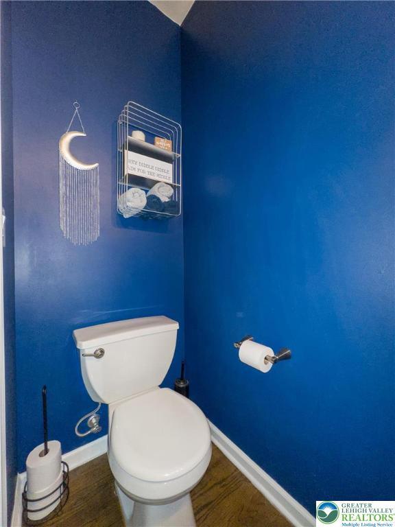 bathroom with baseboards, wood finished floors, and toilet