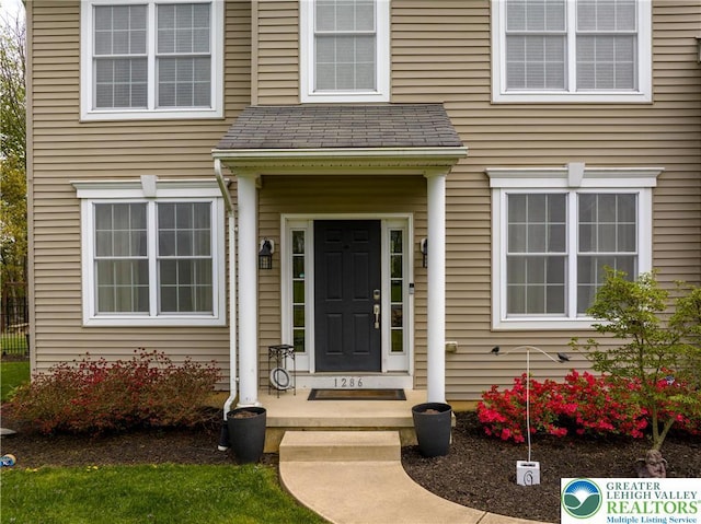 doorway to property featuring roof with shingles