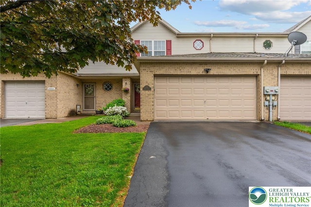 multi unit property with brick siding, a front yard, a garage, and asphalt driveway