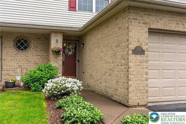 entrance to property with brick siding and a garage