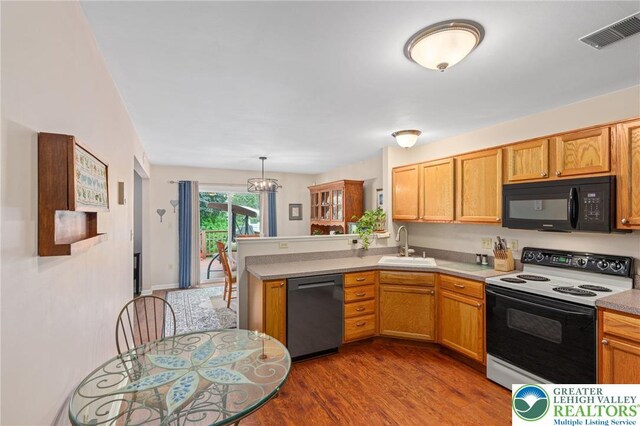 kitchen featuring range with electric cooktop, black microwave, dishwashing machine, a sink, and a peninsula