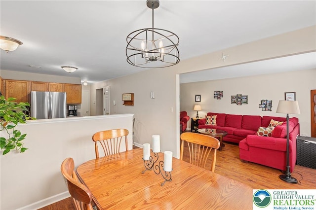 dining area featuring wood finished floors, a chandelier, and baseboards