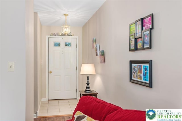 foyer entrance with a chandelier, light tile patterned flooring, and baseboards