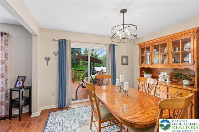 dining room featuring a chandelier, wood finished floors, and baseboards