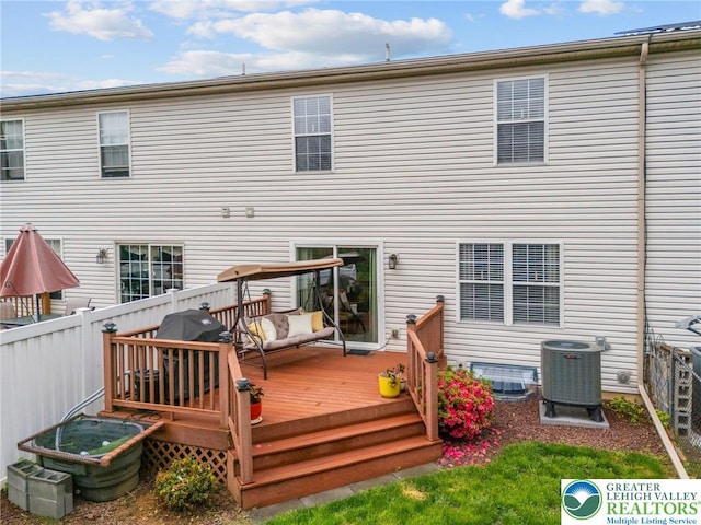 rear view of property with cooling unit, a wooden deck, and fence