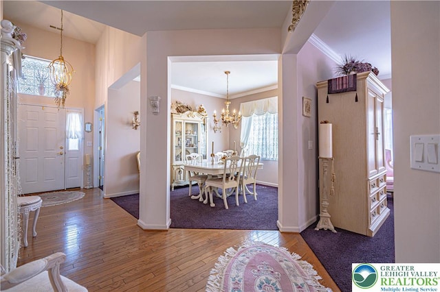 foyer with a chandelier, baseboards, hardwood / wood-style flooring, and crown molding