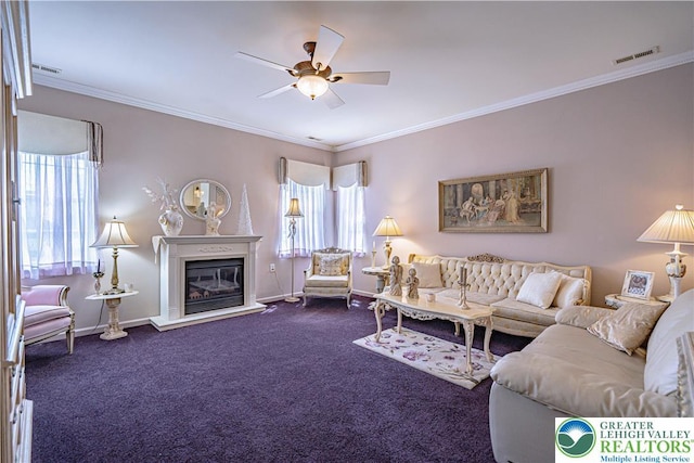 living room with healthy amount of natural light, ceiling fan, dark colored carpet, ornamental molding, and baseboards