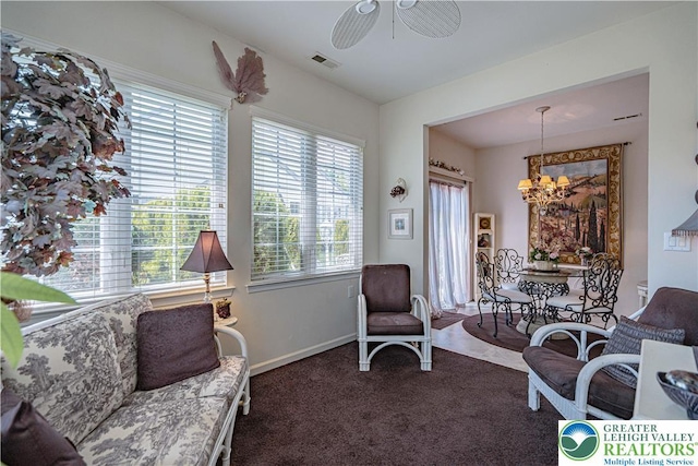 living area featuring a chandelier, carpet, a ceiling fan, and baseboards