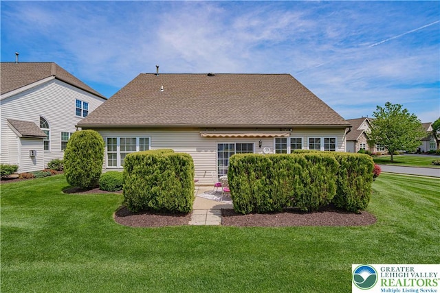 back of property with a lawn, roof with shingles, and a patio