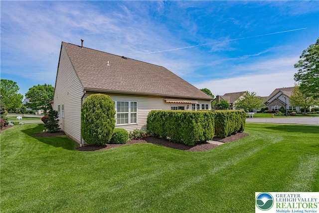 view of property exterior with a lawn and a shingled roof