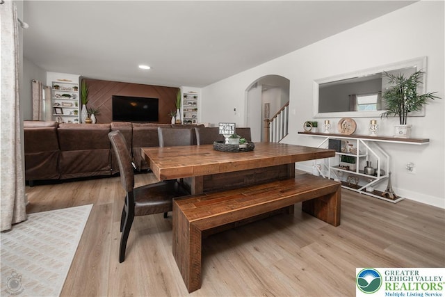 dining area featuring light wood finished floors, arched walkways, recessed lighting, stairway, and baseboards