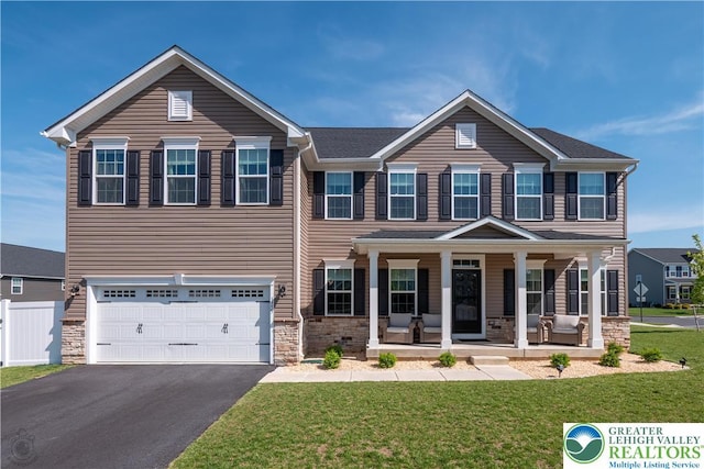 view of front of property featuring a porch, stone siding, driveway, and an attached garage