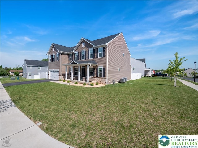 view of front facade with central air condition unit, asphalt driveway, a garage, a front yard, and stone siding