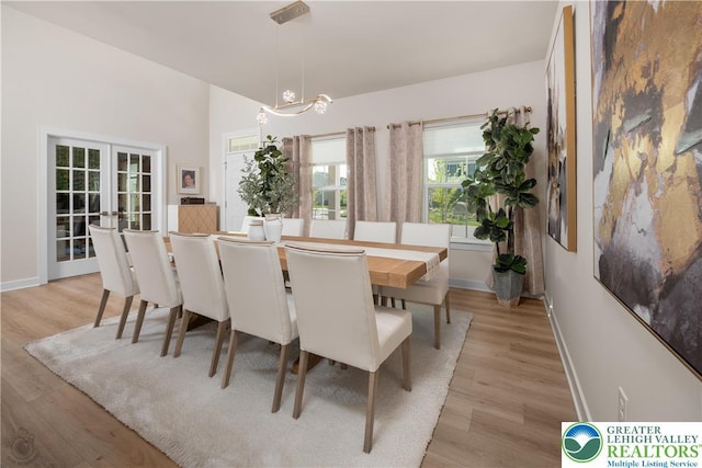 dining area featuring french doors, light wood-style flooring, and baseboards