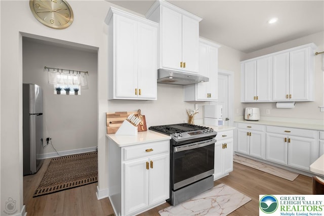 kitchen featuring stainless steel appliances, under cabinet range hood, light wood-style flooring, white cabinets, and recessed lighting