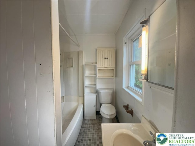 bathroom with toilet, a tub, and tile patterned floors