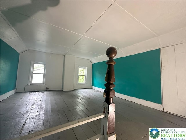 additional living space featuring healthy amount of natural light, hardwood / wood-style floors, vaulted ceiling, and baseboards