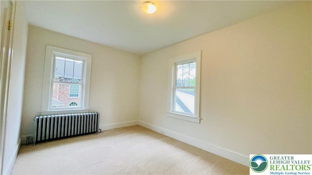 carpeted spare room featuring radiator and baseboards