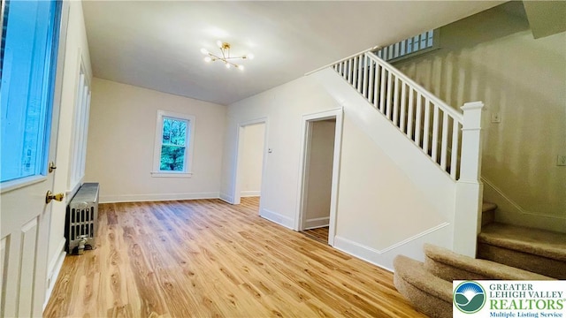 entrance foyer featuring stairway, wood finished floors, radiator, and a chandelier
